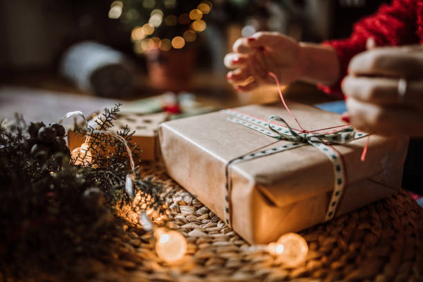 young woman wrapping christmas gifts in living room